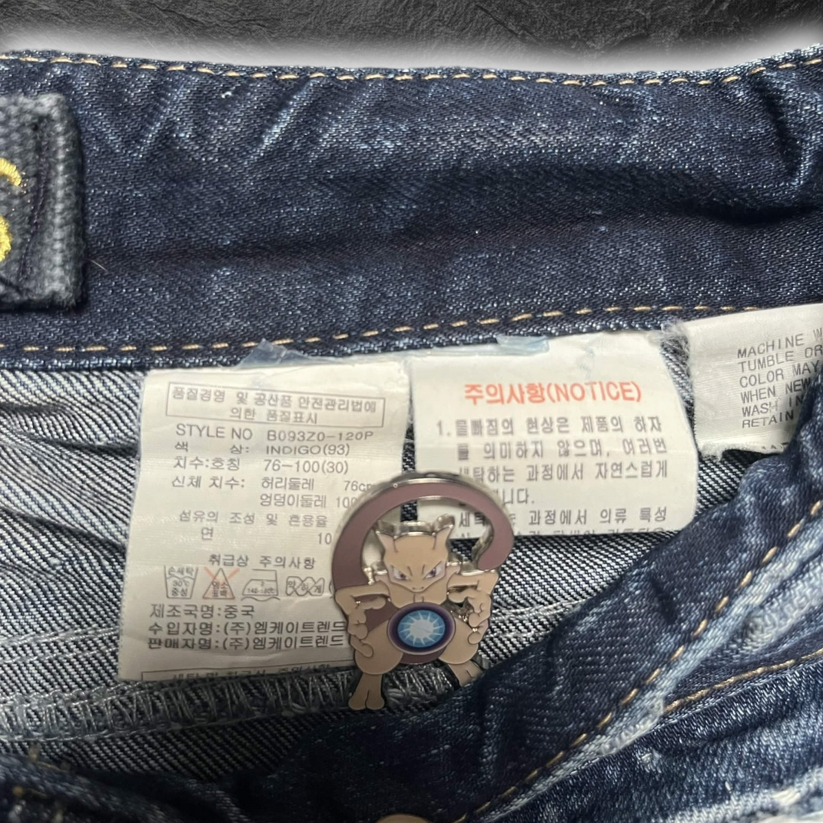 streetcave.eu Buckaroo Jeans aus Indigo-Denim mit Pflegeetiketten und einem kleinen Mewtu-Anstecker am Bund