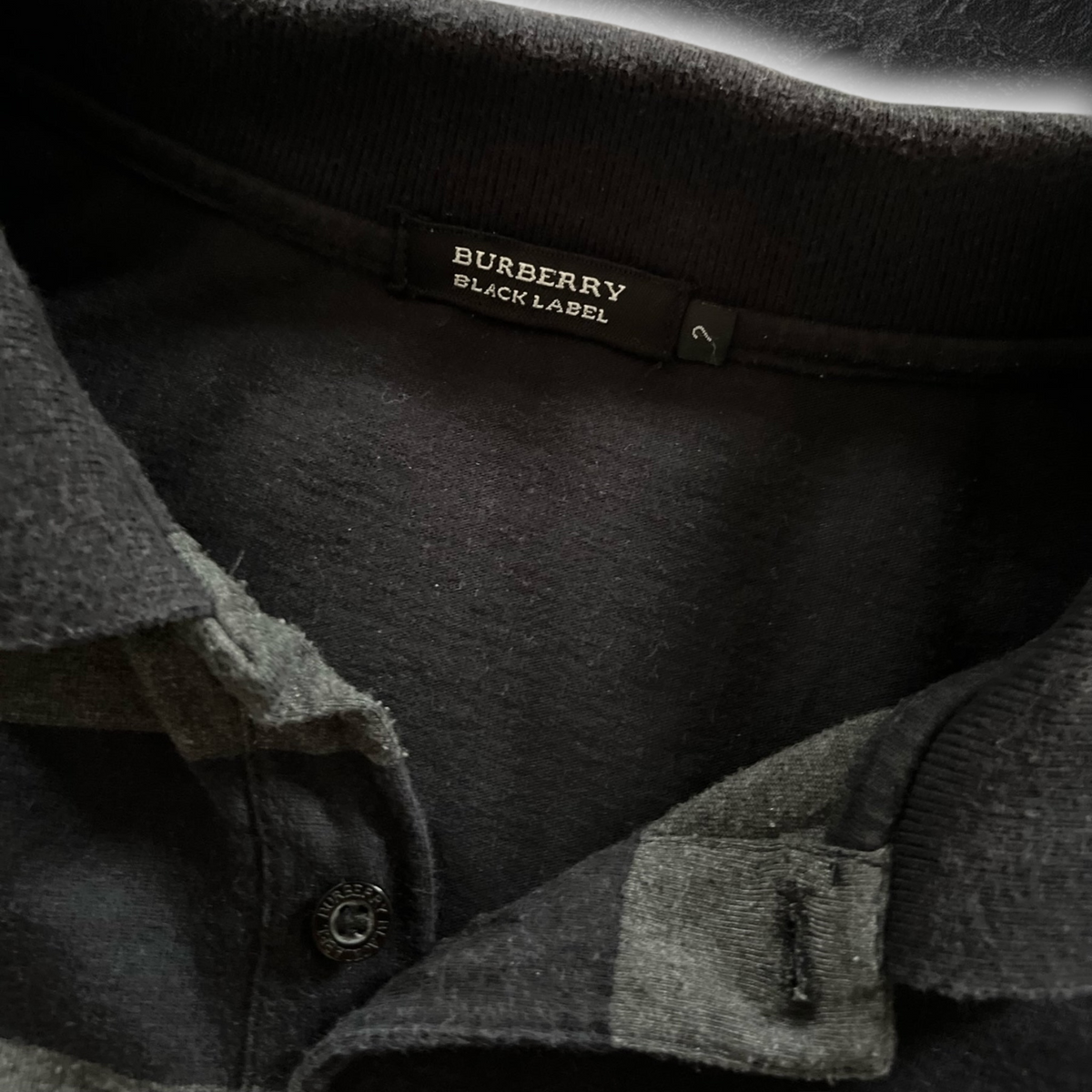 streetcave.eu Burberry Black Label Poloshirt in Schwarz und Grau mit Markenlogo am Kragen und gravierten Knöpfen